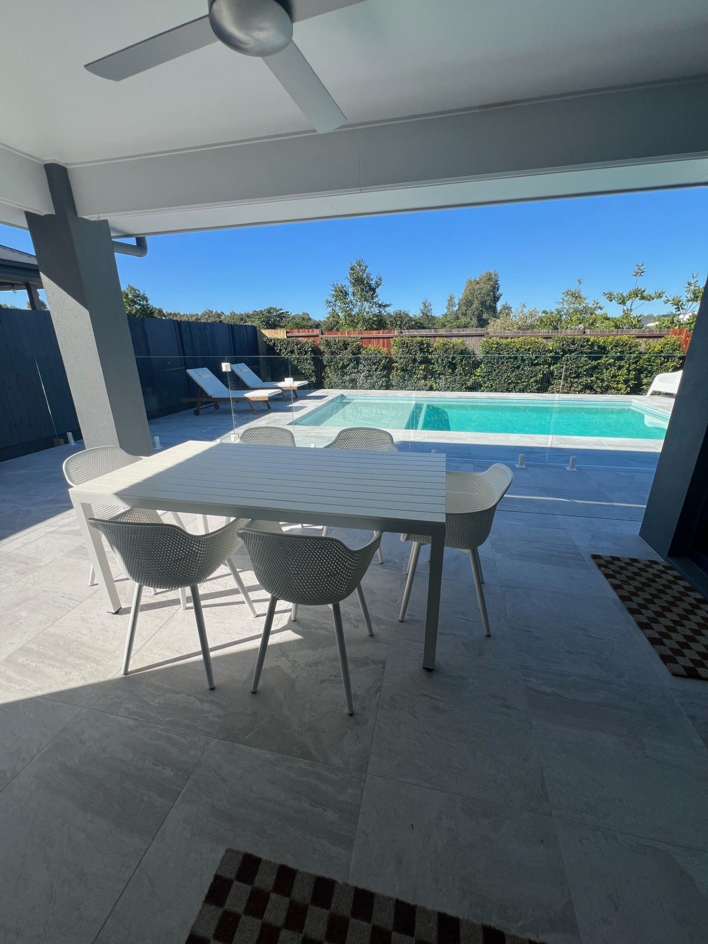 Outdoor patio with table, chairs, and swimming pool in background.
