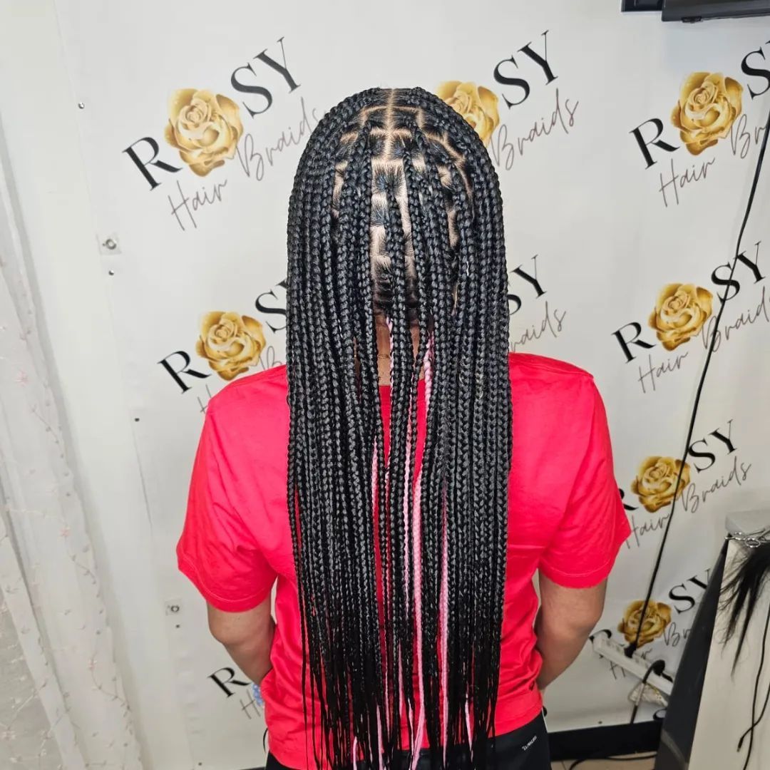 A woman in a red shirt has braids in her hair