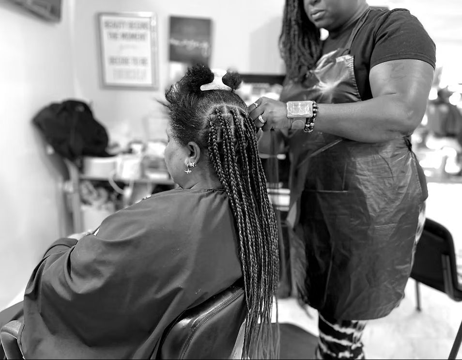 A woman is getting her hair braided in a salon.
