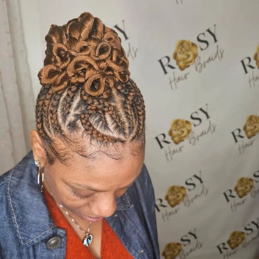 A woman with braids in her hair is standing in front of a sign that says rosy hair braids