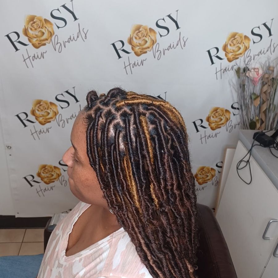 A woman is sitting in front of a sign that says rosy hair braids