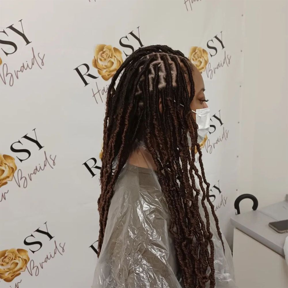 A woman with dreadlocks is wearing a mask in front of a wall that says rosy braids.