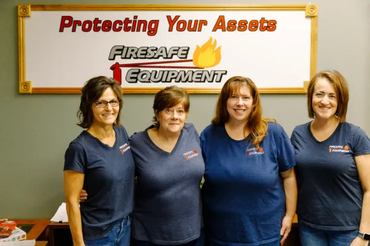 Four women standing in front of a sign that says protecting your assets