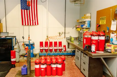 A bunch of red fire extinguishers are lined up in a room