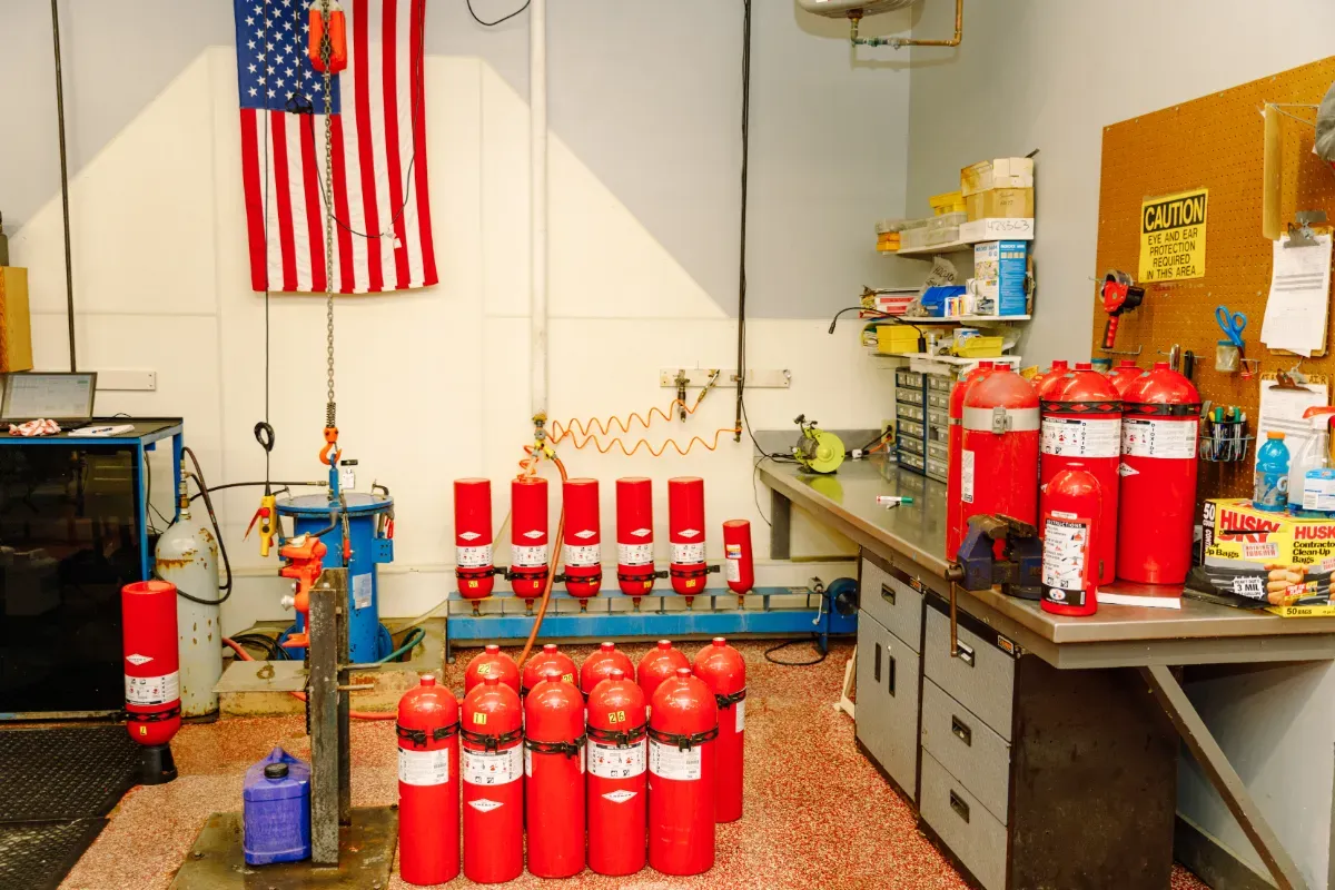 A room with a bunch of red fire extinguishers and an american flag