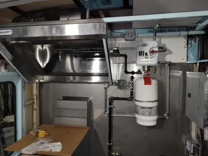 A stainless steel kitchen with a propane tank on the wall
