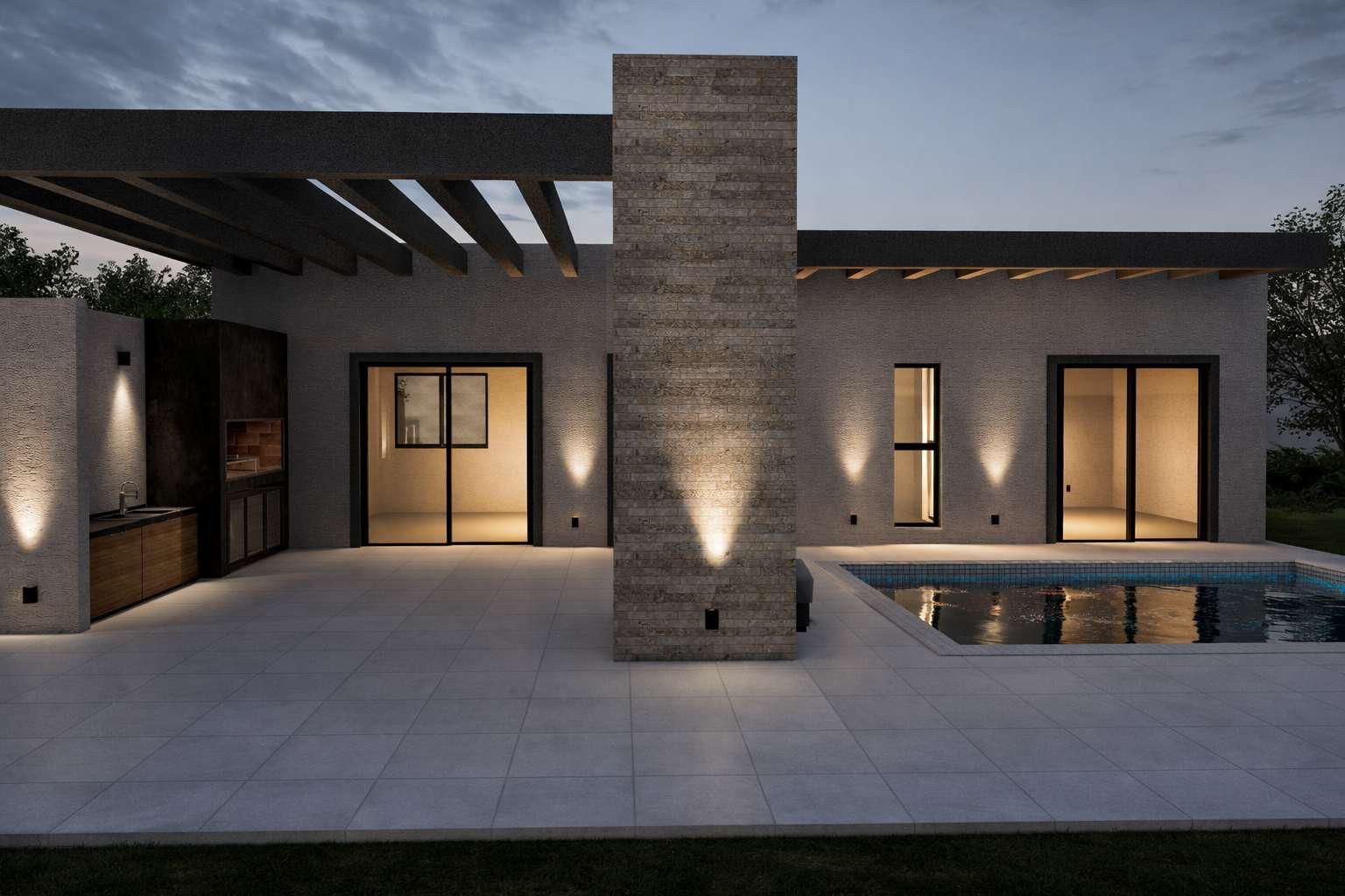 Exterior de una casa moderna al anochecer, con fachada de piedra, patio, piscina e iluminación exterior cálida.
