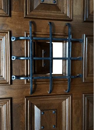 A wooden door with a metal grille on it