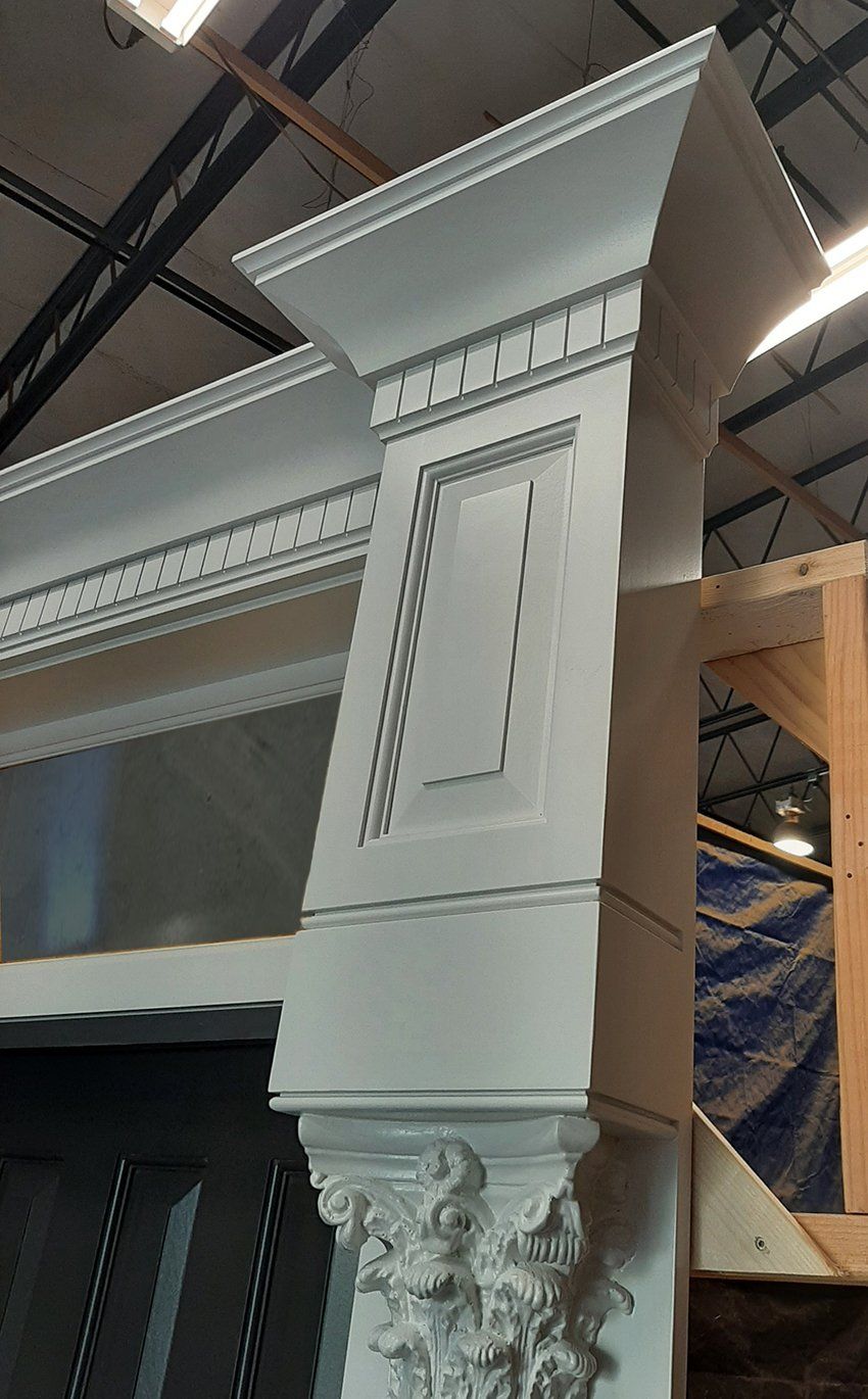 A white column with a statue on it is sitting in a warehouse.