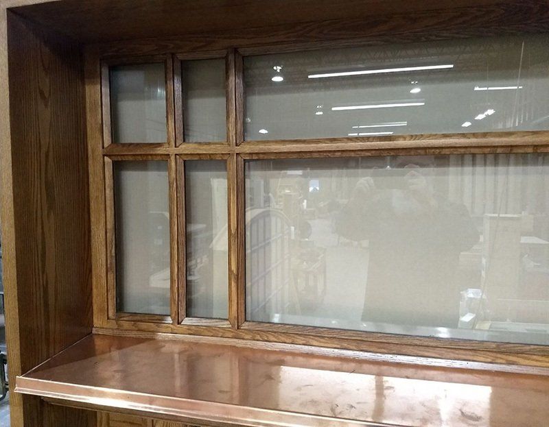 A wooden cabinet with a copper counter top and a window.