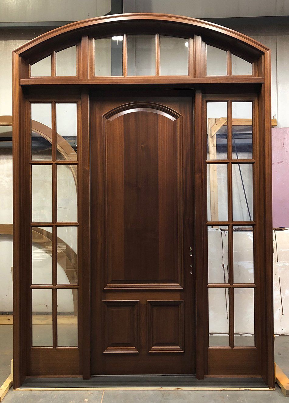 Solid mahogany wood two panel door unit features 8 lite sidelites and arch top transom