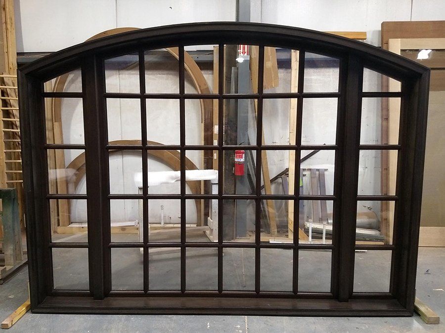 A large window with a curved top is sitting in a room