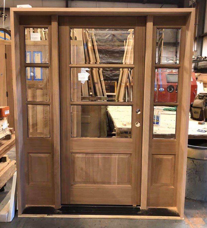 A wooden door with a lot of windows is sitting in a warehouse.
