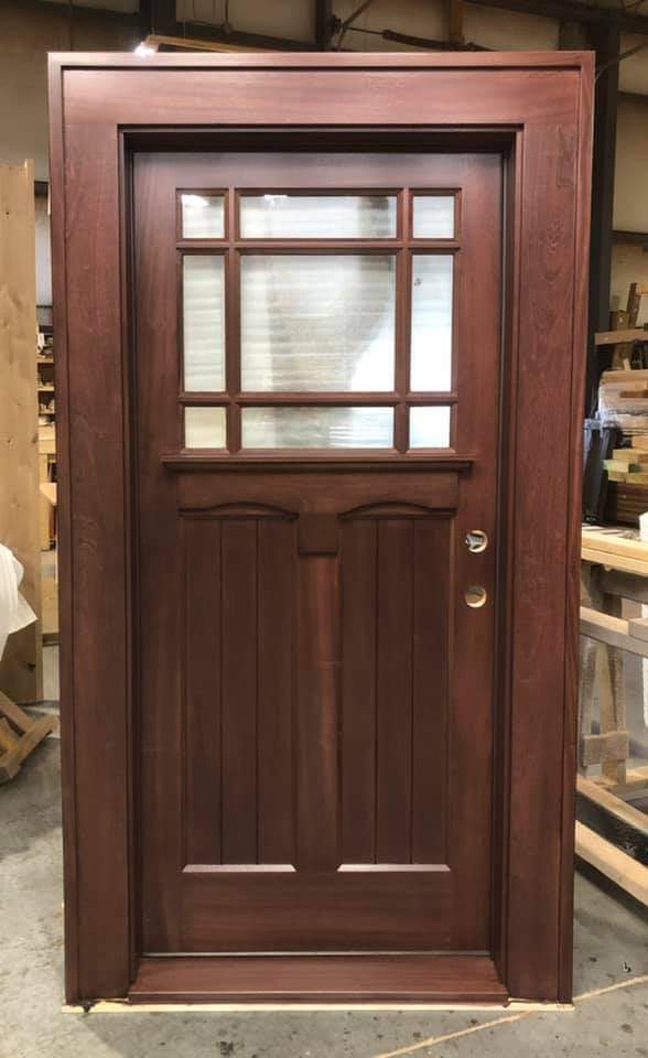 A wooden door with a glass window is sitting on a table.