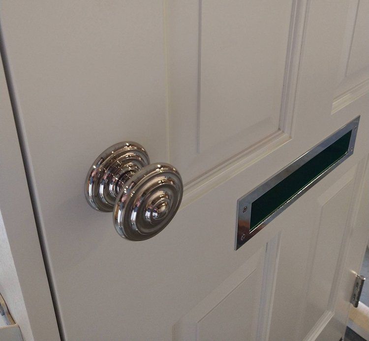 A white door with a chrome door knob and mail slot