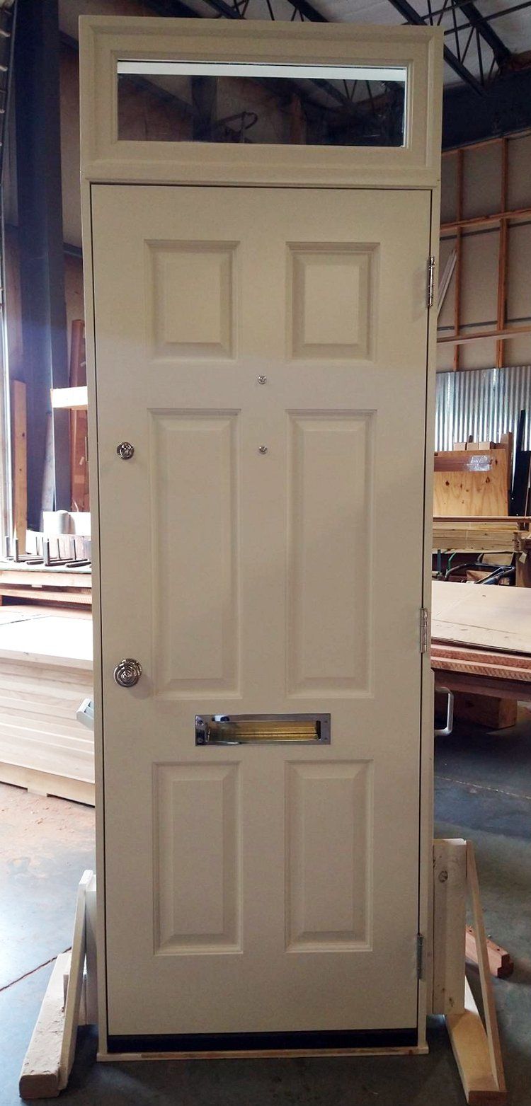 A white door is sitting on a wooden stand in a warehouse.