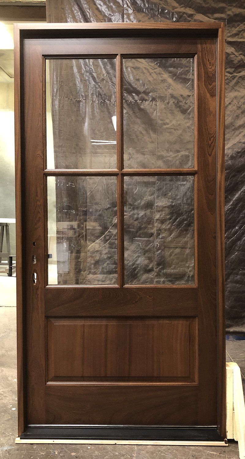 A wooden door with four windows is sitting on a wooden floor.