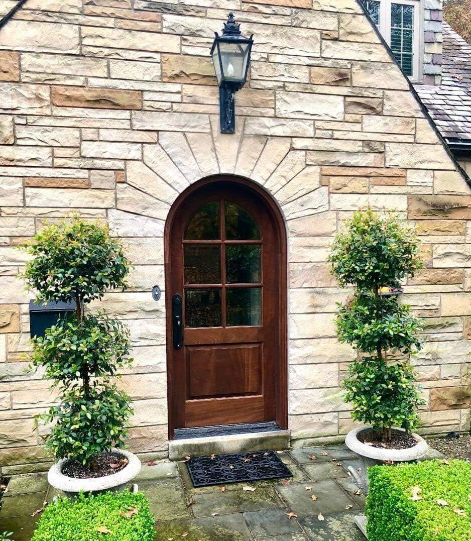 A brick building with a wooden door and trees in front of it.