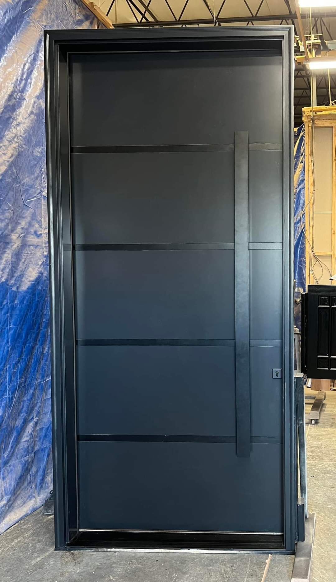 A black door with a handle is sitting on top of a concrete floor.