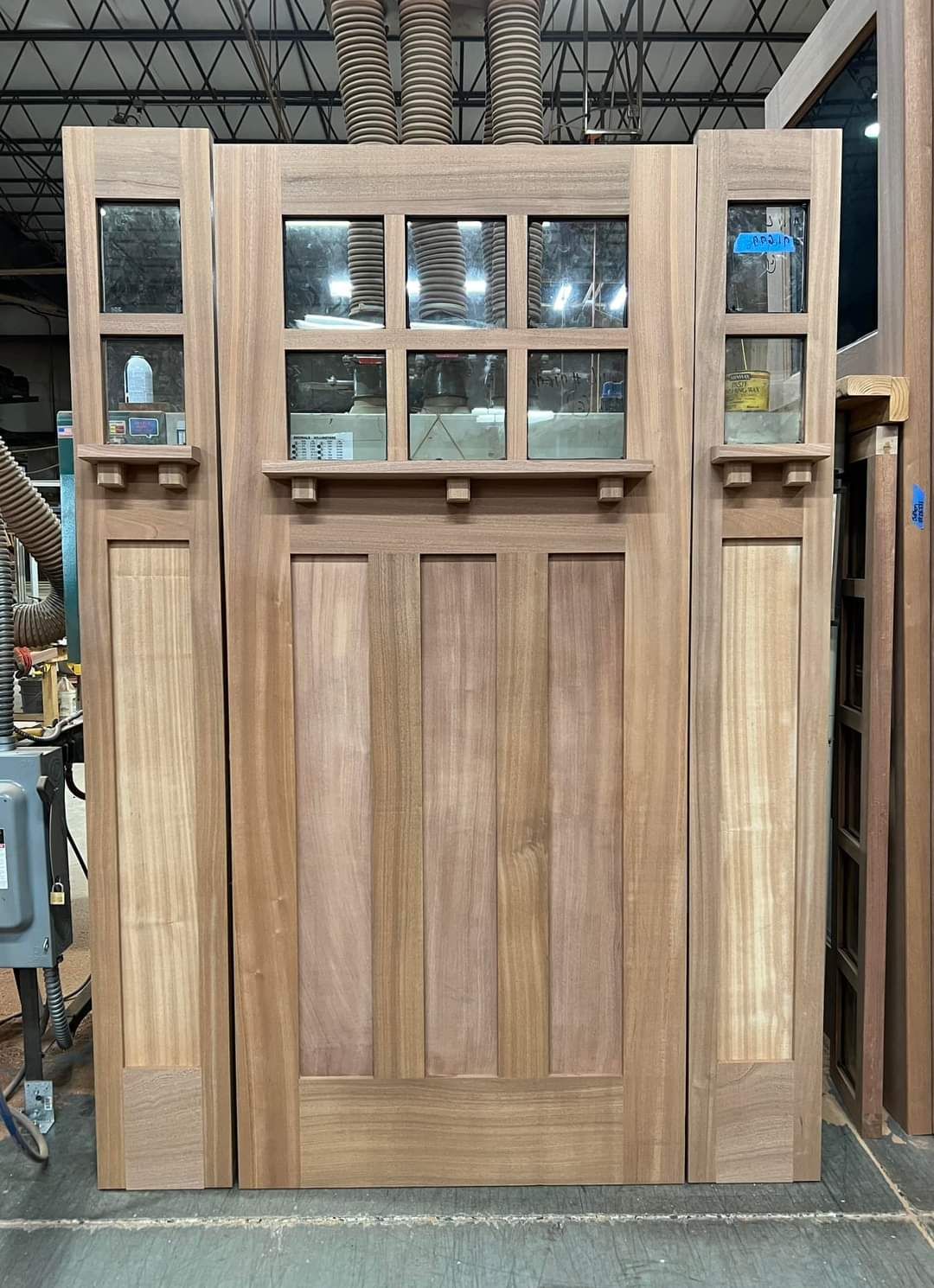 A wooden door with glass windows is sitting in a warehouse.