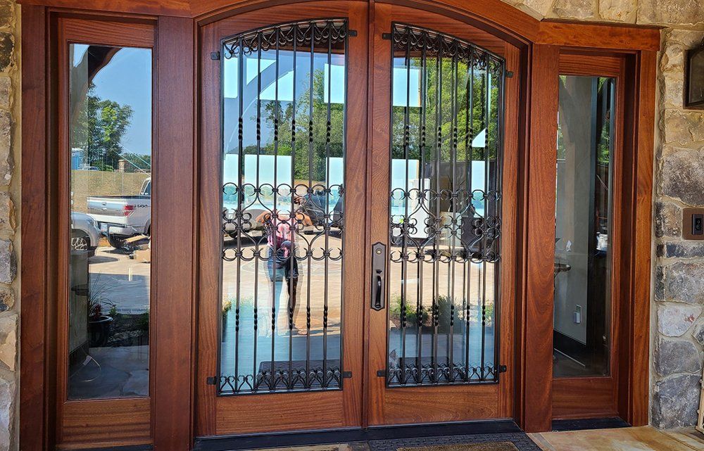 Mahogany archtop exterior double door with custom forging and sidelights