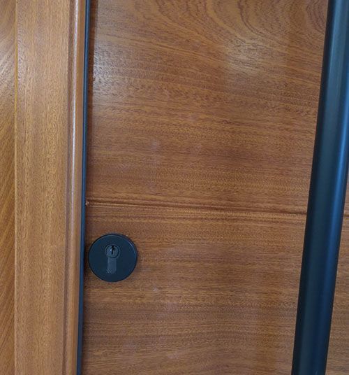 A close up of a wooden door with a black handle.
