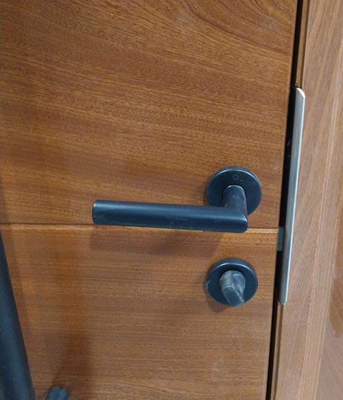 A close up of a door handle on a wooden door.