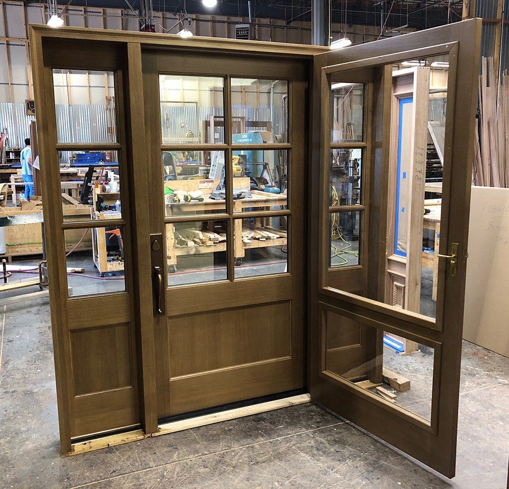 A wooden door with glass panels is being built in a workshop