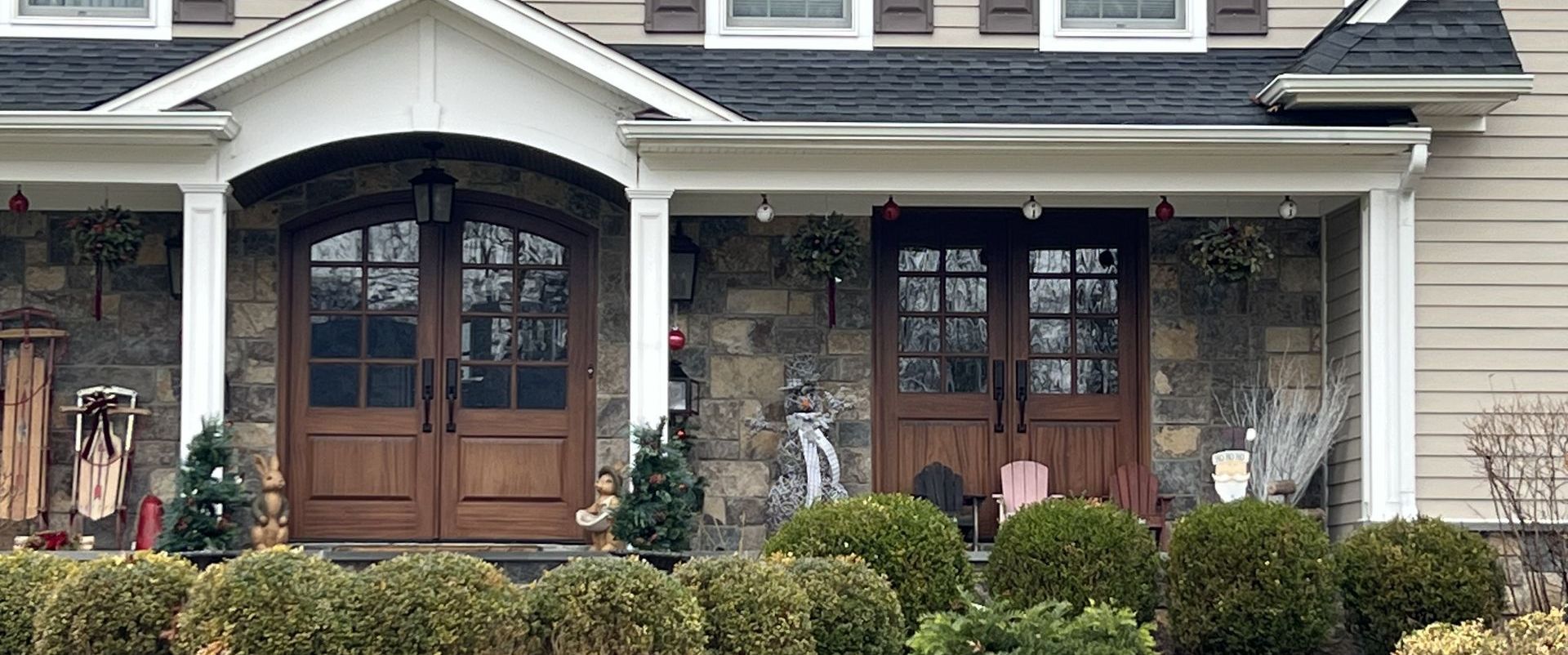 The front of a house with a porch and two wooden doors.