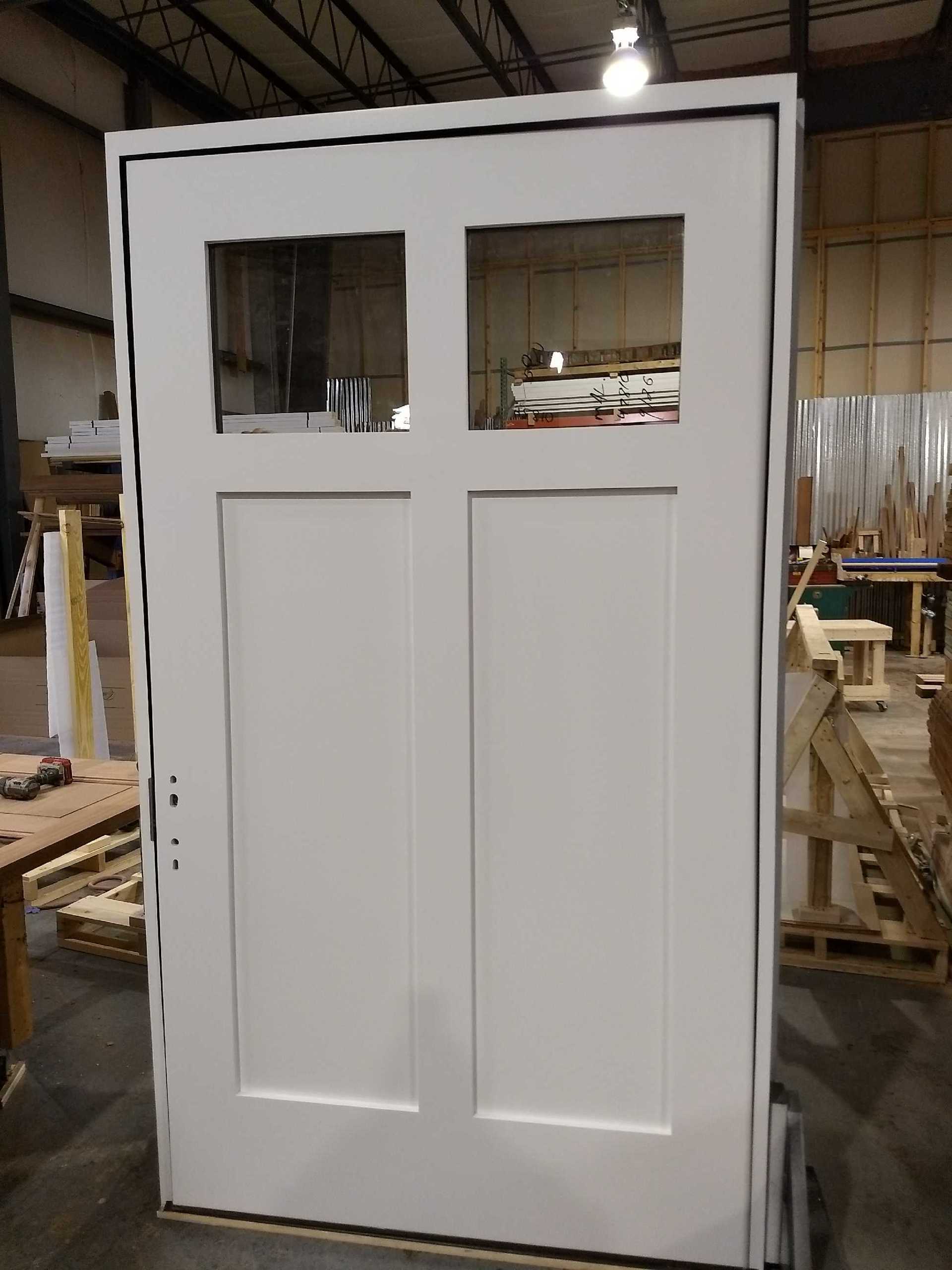 A white door with two windows is sitting in a warehouse