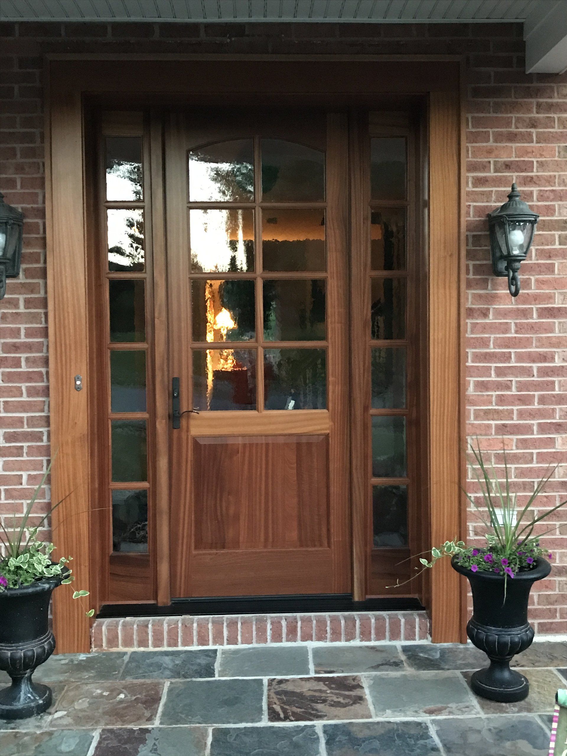 A brick building with a wooden door and two potted plants in front of it.