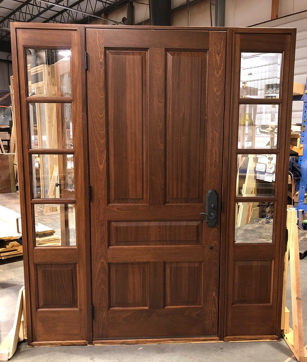 A wooden door with glass panels is sitting in a warehouse