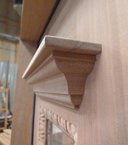 A wooden mantle with a mirror on it