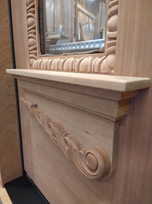 A wooden mirror with a shelf underneath it on a wooden wall.