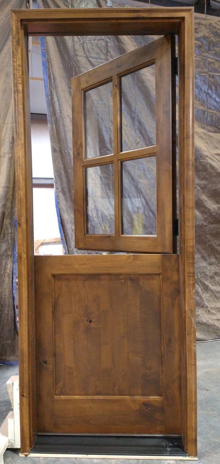 A wooden door with a glass window is sitting on a concrete floor.