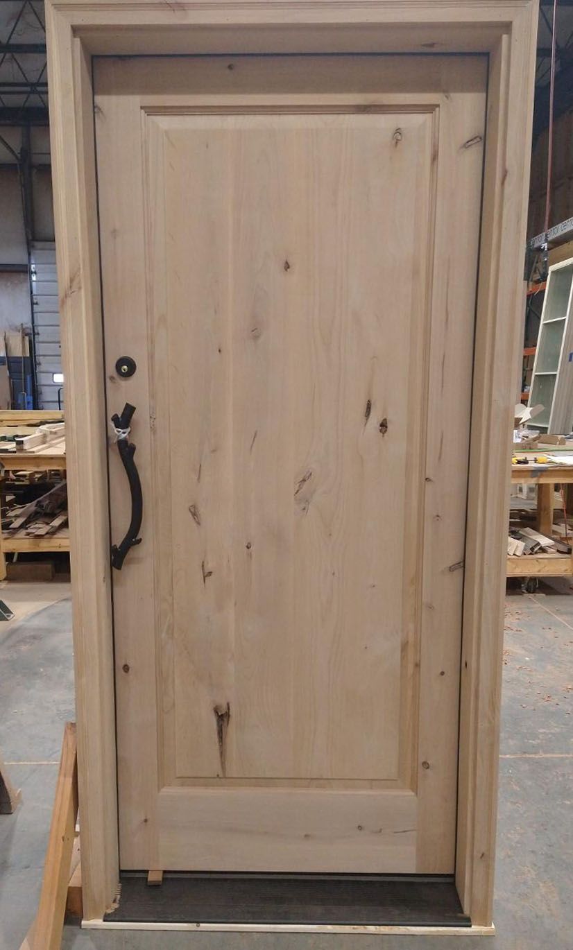 A wooden door is sitting on top of a wooden pallet in a warehouse.