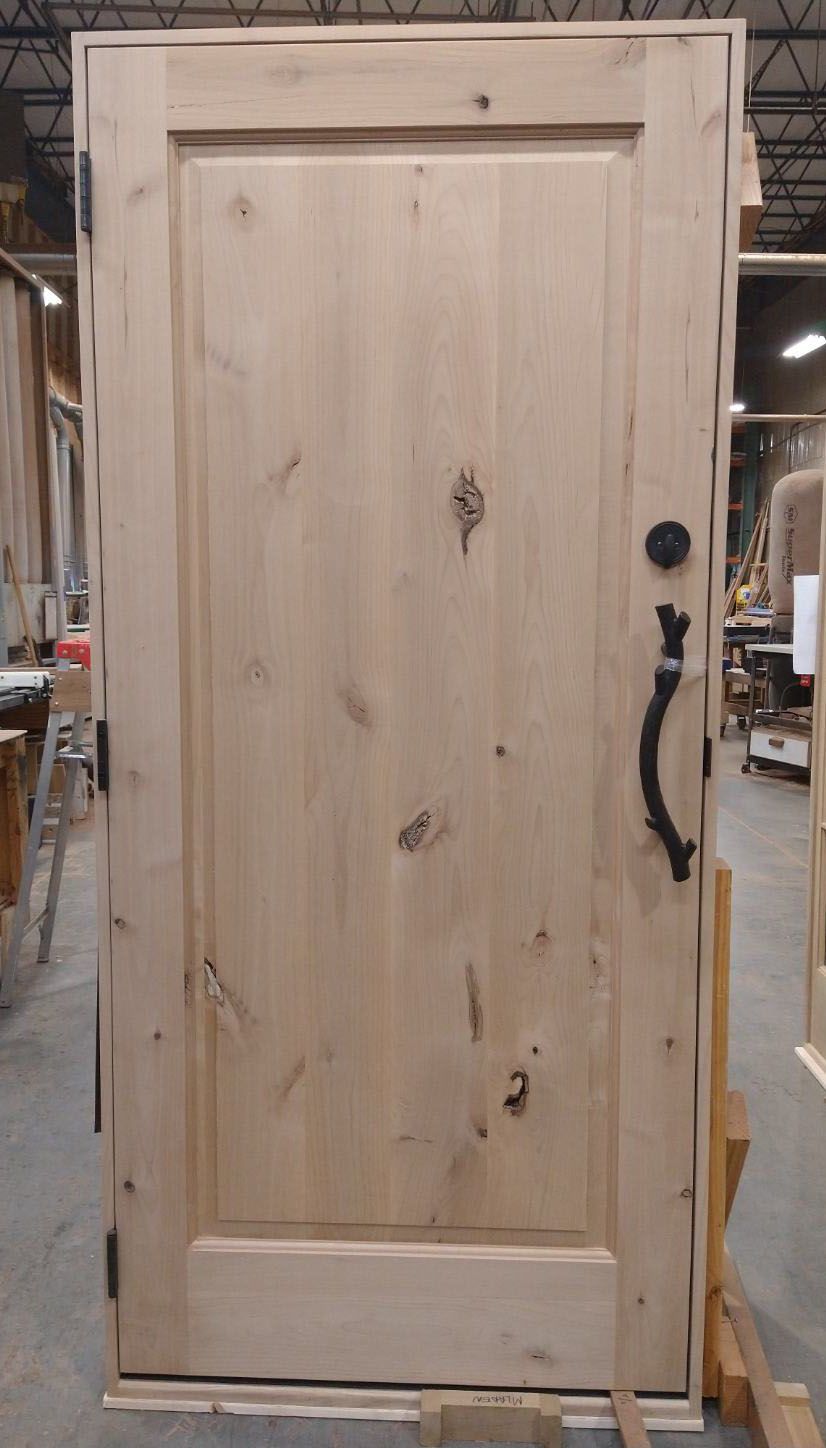 A wooden door with a black handle is sitting on top of a wooden table.