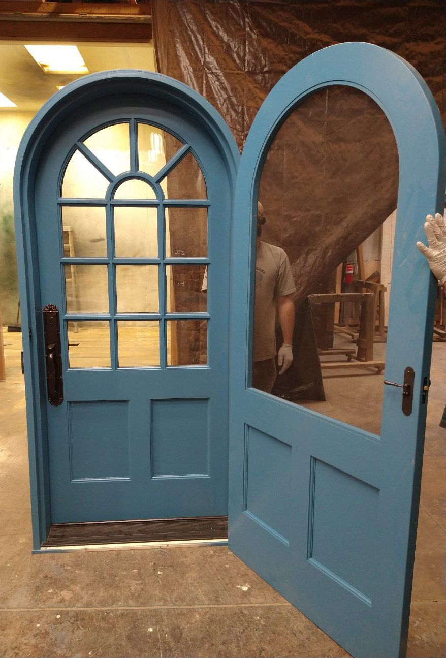 A man is standing behind a blue door that is open.