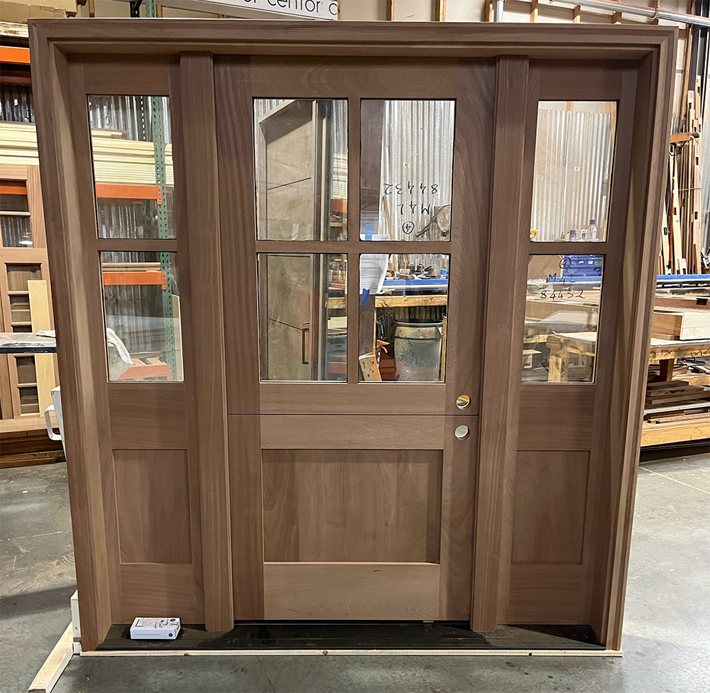 A wooden door with glass panels is sitting in a warehouse.