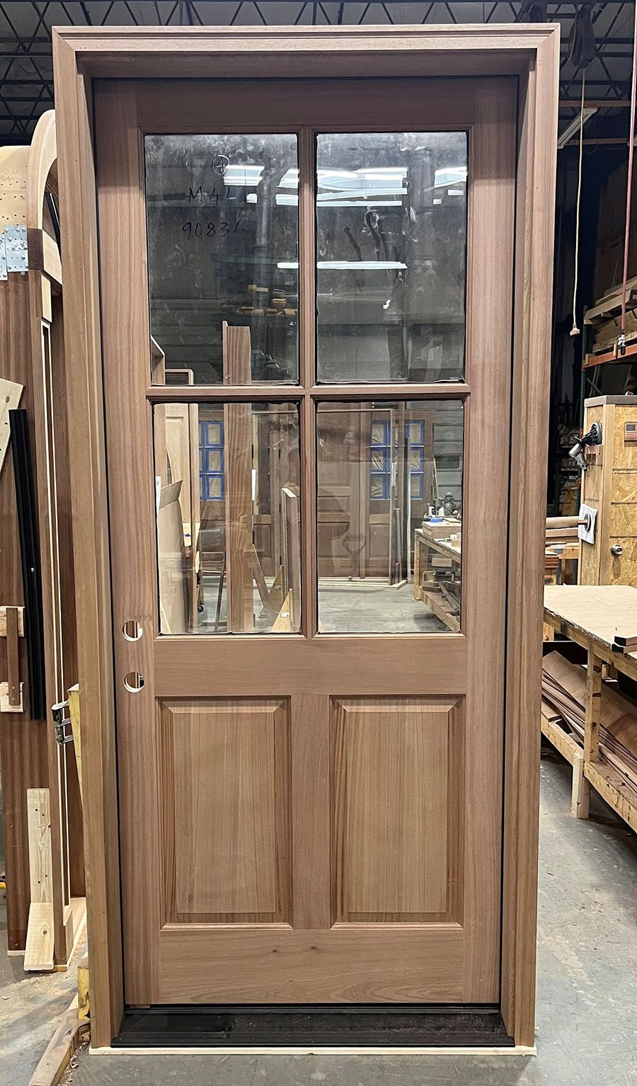 A wooden door with four windows is sitting in a woodworking shop.
