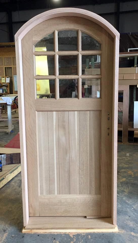 Arched top single pre-hung wood door with 9 panes of glass in top third