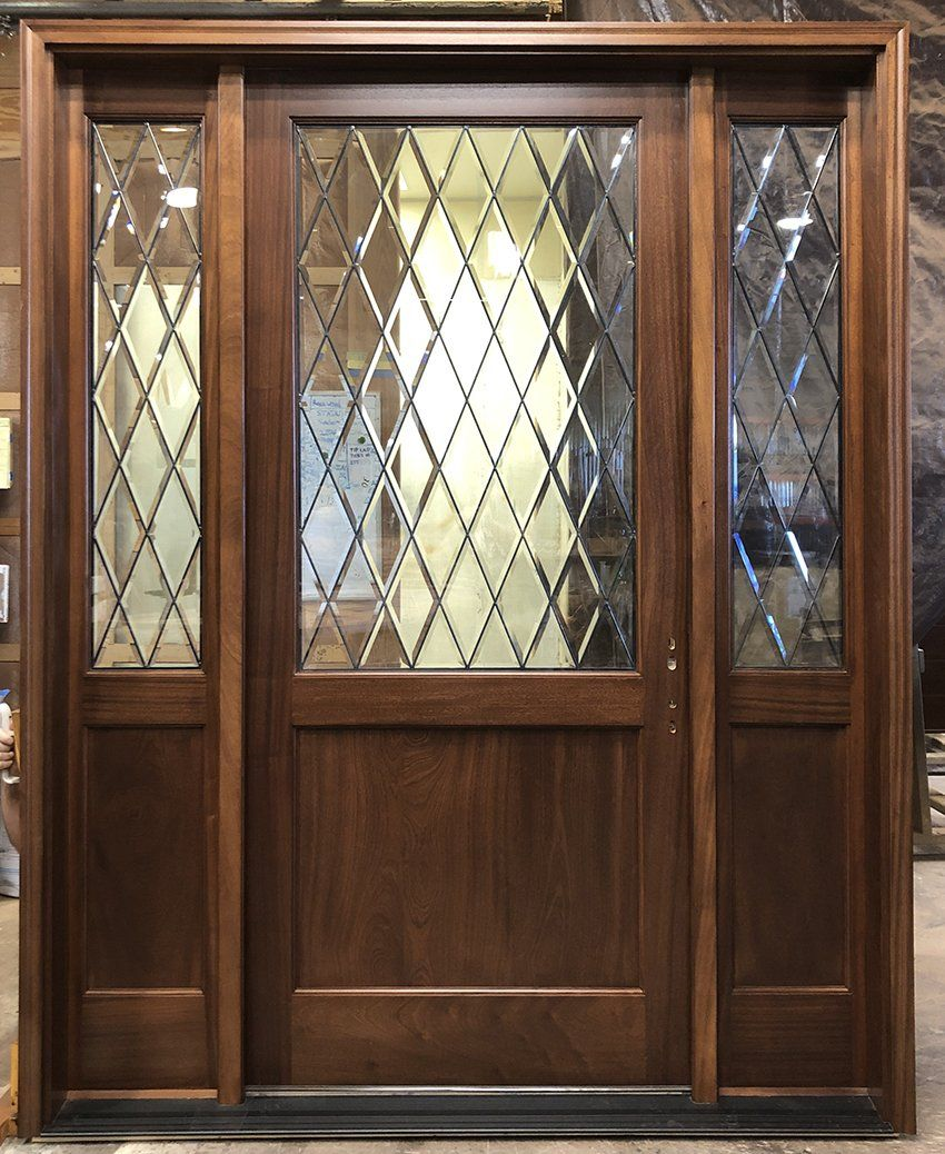 A wooden door with a stained glass design is sitting in a room.