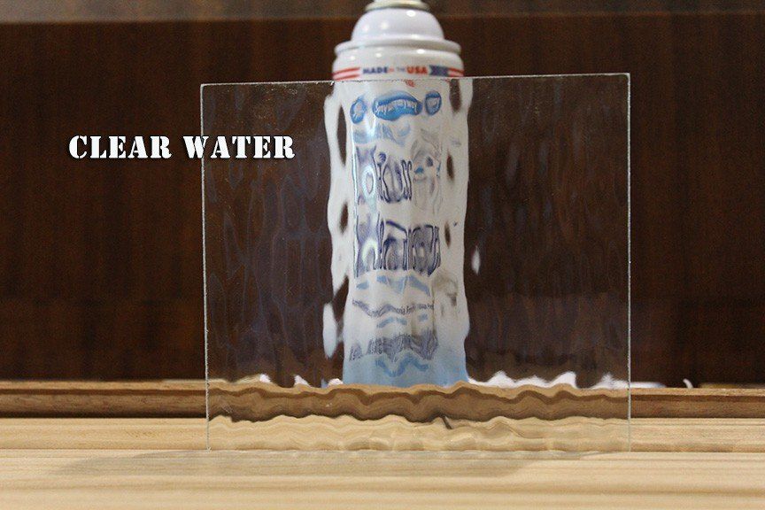 A can of clear water is sitting on a wooden table.