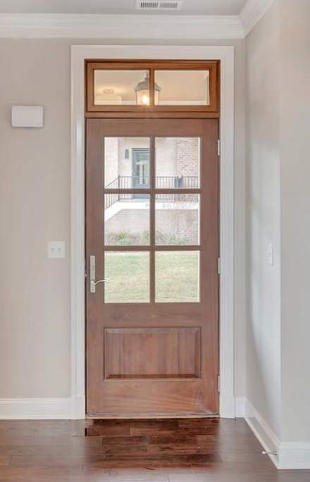 An empty room with a wooden door and a window above it