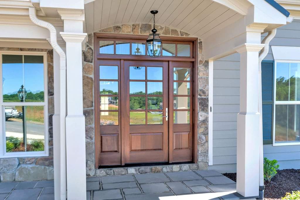 The front door of a house with a porch and a wooden door.