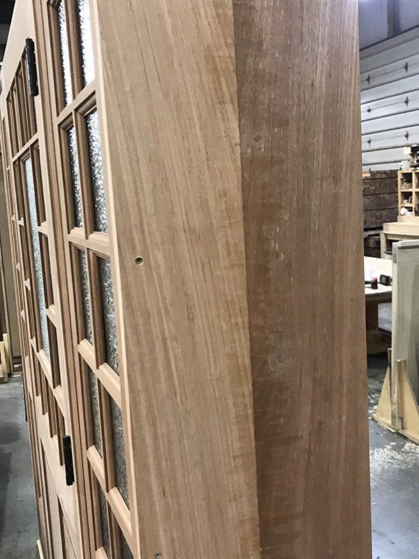 A wooden door with a lot of windows is being built in a factory.
