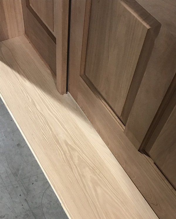 A close up of a wooden door with a wooden floor in front of it.