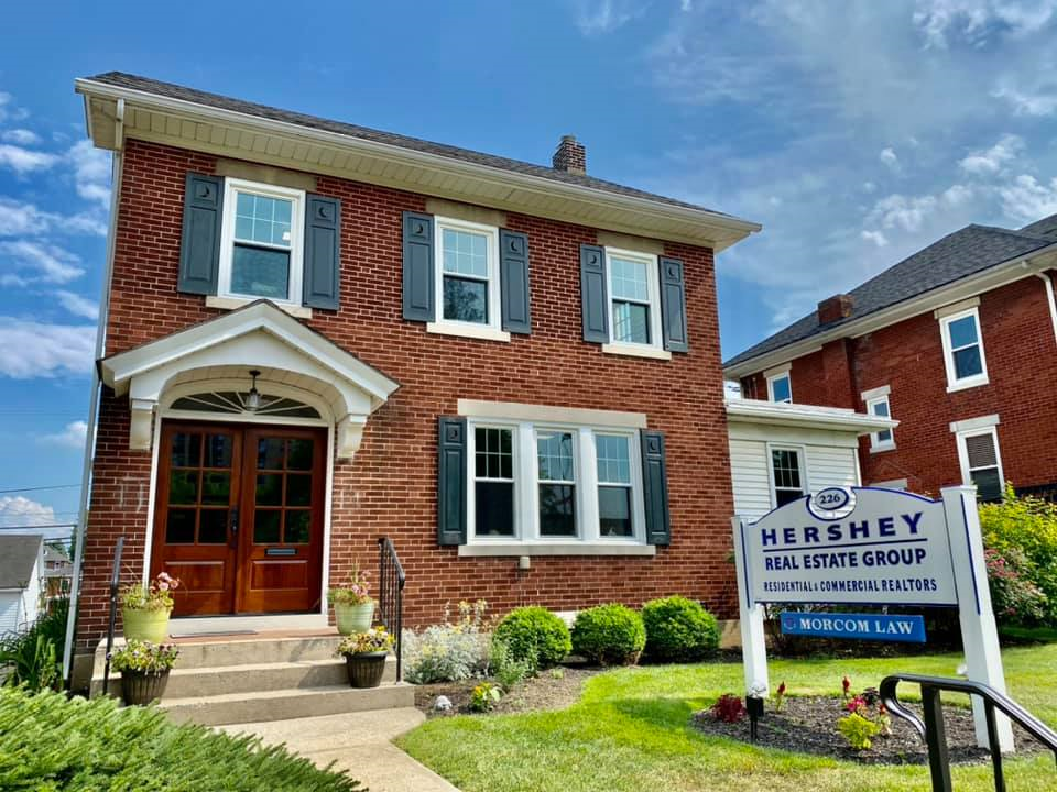A brick house with a sign in front of it that says `` hershey real estate group ''.