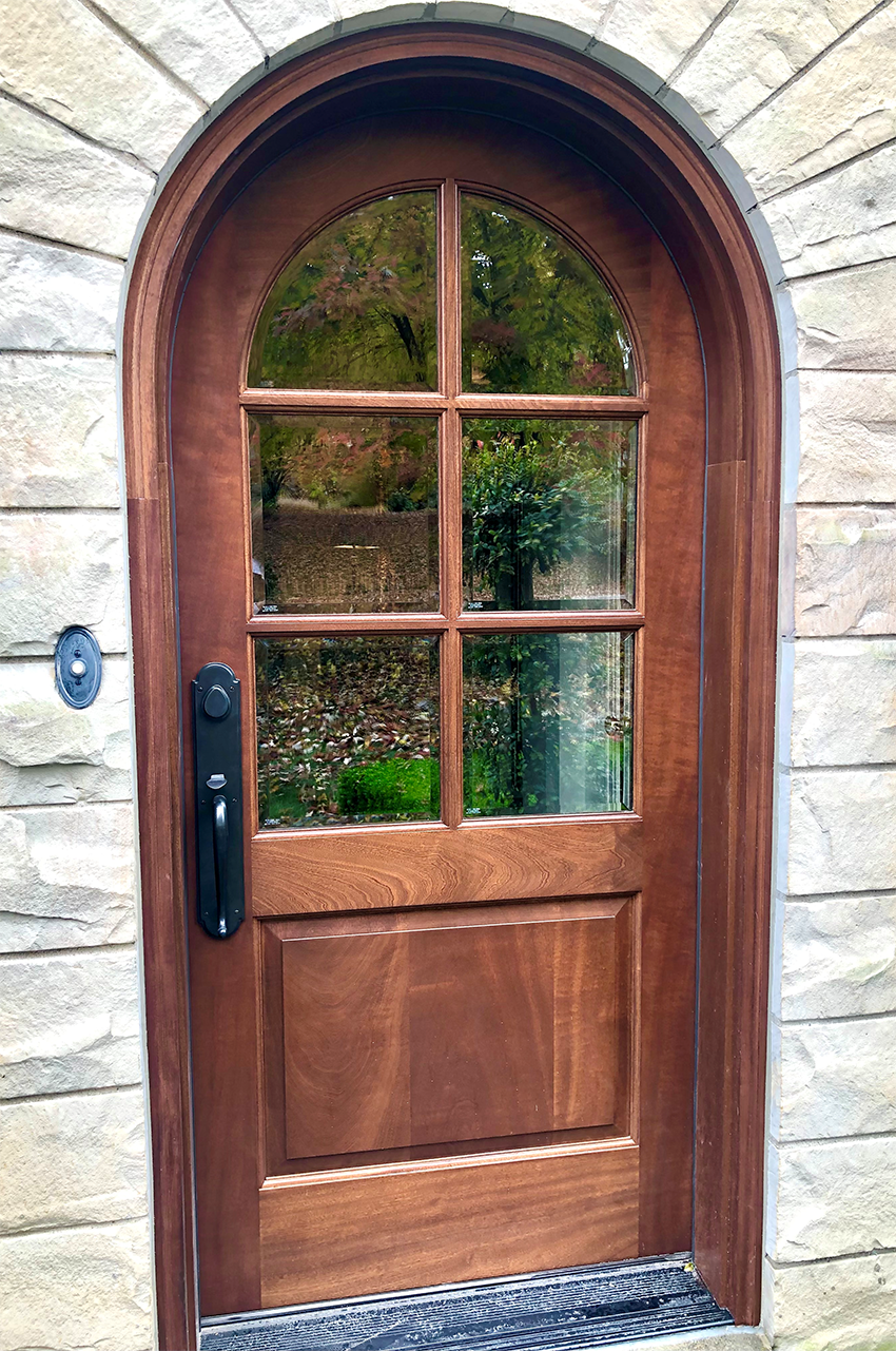 A wooden door with a glass window on a stone wall.