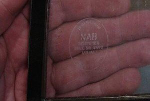 A person is holding a piece of glass that says nab on it
